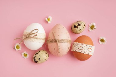 Pembe arka planda papatya çiçekli Paskalya yumurtaları.