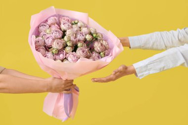 Sarı arka planda güzel güller alan bir kadın.