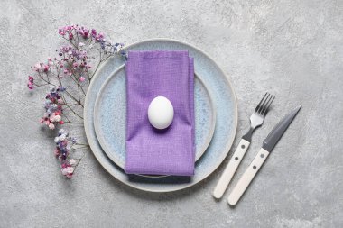 Paskalya için çok güzel bir sofra. Gri arka planda yumurta ve çiçekler var.