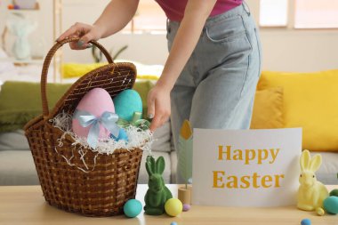 Paskalya yumurtalı kadın, oyuncak tavşanlar ve masadaki tebrik kartı, yakın plan.