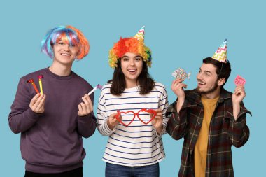 Mavi arka planda düdük ve kağıt etiketli komik kılık değiştirmiş genç arkadaşlar. 1 Nisan kutlamaları