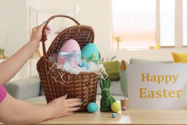 Paskalya yumurtalı kadın, oyuncak tavşanlar ve masadaki tebrik kartı, yakın plan.