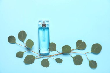 Mavi arka planda yaprakları olan bir şişe parfüm. Üst görünüm