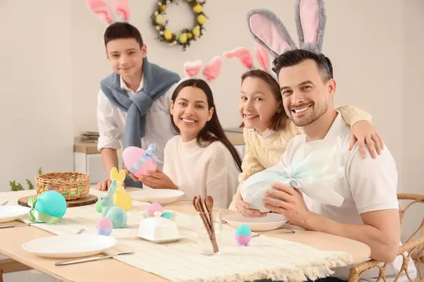 Happy family with gift eggs in dining room on Easter Day