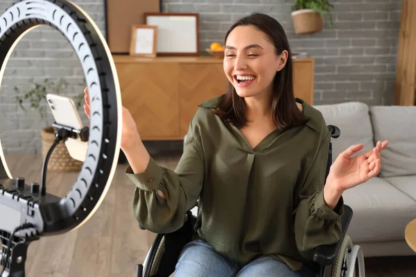 Female blogger in wheelchair recording video at home