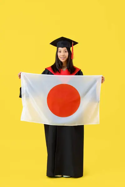 Female Asian graduate with flag of Japan on yellow background