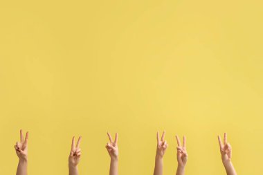 Sarı arka planda barış hareketlerini gösteren kadın elleri