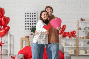 Young couple with paper hearts having date at home. Valentine's day celebration