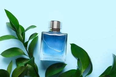 Mavi arka planda bitkisi olan mavi bir parfüm şişesi. Yakın çekim.