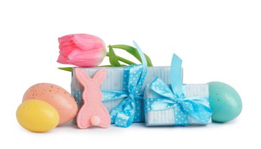 Paskalya yumurtaları, kumaş tavşanı, lale ve beyaz arka planda hediyeler