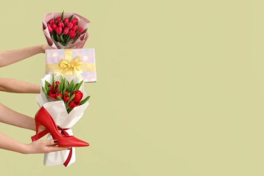 Lale buketleri, hediye kutusu ve yeşil arka planda yüksek topuklu ayakkabı olan kadın elleri. Uluslararası Kadınlar Günü için Alışveriş