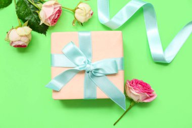 Yeşil arka planda güzel gülleri ve kurdelesi olan hediye kutusu. Uluslararası Kadınlar Günü