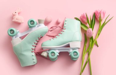 Paskalya yumurtalı klasik patenler, oyuncak tavşan ve pembe arka planda güzel laleler.