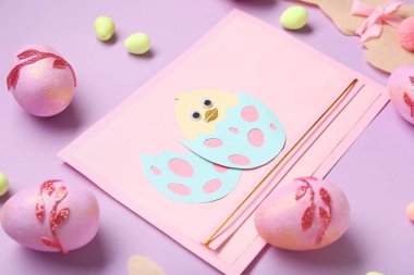 Paskalya tavşanları, boyalı yumurtalar ve eflatun kaplama tavuklu kartlar. Yakın çekim.