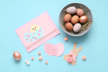 Sepette Paskalya yumurtası, kağıttan tavşan ve mavi arka planda tavuk. Üst görünüm