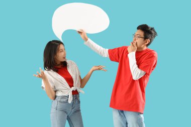 Mavi arka planda boş konuşma balonu olan Asyalı genç arkadaşlar