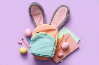 Paskalya yumurtalı tavşan kulakları ve leylak arka planda okul malzemeleri.