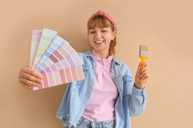 Renkli paletleri ve bej arka planda fırçası olan genç bir kadın. Onarım kavramı