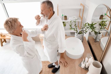 Banyoda dişlerini fırçalayan olgun bir çift.