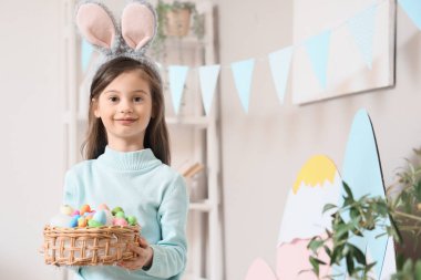 Evde paskalya yumurtası dolu sepetli şirin küçük bir kız.
