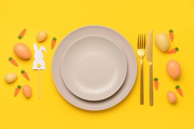 Güzel Paskalya sofrası. Sarı arka planda yumurtalar, oyuncaklar ve tavşanlarla servis ediliyor.