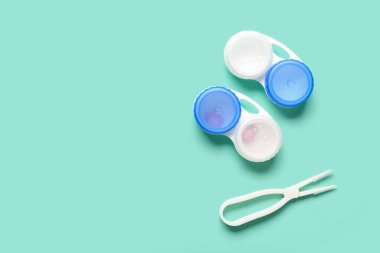 Turkuaz arka planda kontak lensler ve cımbızla konteyner