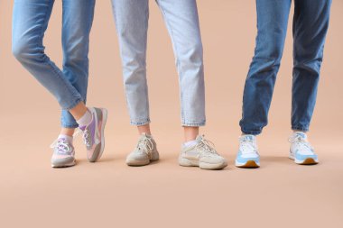 Bej arka planda farklı ayakkabılar giyen kadın bacakları.