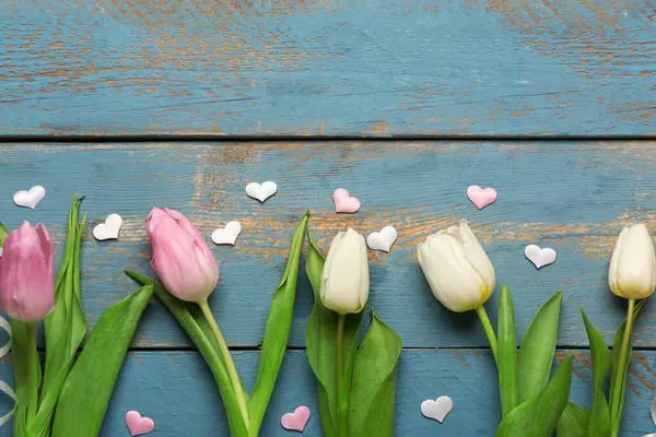 Mavi ahşap arka planda kalpleri olan lale çiçekleri. Uluslararası Kadınlar Günü kutlamaları