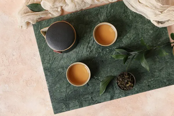 Bir fincan sıcak çay, kuru yapraklı kase ve arka planda çaydanlık.