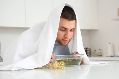 Genç adam mutfaktaki masada buhar solumuş.