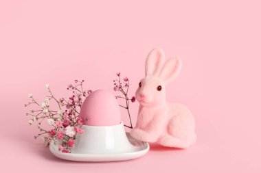 Paskalya yumurtası boyalı tutucu, pembe arka planda tavşan ve çigila çiçekleri