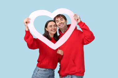 Mavi arka planda kalp şeklinde bir çerçeveye sahip genç bir çift. Sevgililer Günü kutlaması