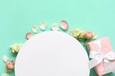 İçinde hediye kutusu olan boş bir kart, turkuaz arka planda güller ve yapraklar.