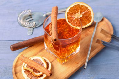 Lezzetli bir bardak eski moda kokteyl ve mor ahşap arka planda portakal dilimleri.