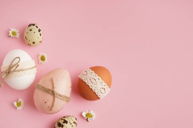 Pembe arka planda papatya çiçekli Paskalya yumurtaları.