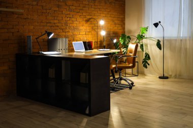 Karanlık ofis, iş yeri, boş laptop ve geceleri parlayan lambalar.