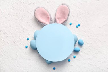 Paskalya yumurtalı tavşan kulakları ve beyaz grunge arka planında boş tebrik kartı.