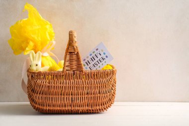 Hediye çantalı hasır sepet ve arka planda Paskalya kartı.