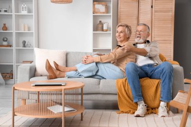 Evde kanepede televizyon izleyen olgun bir çift.