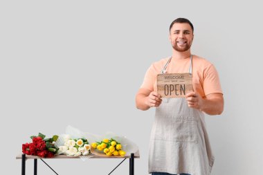 Genç adam arka planda çiçek satıyor