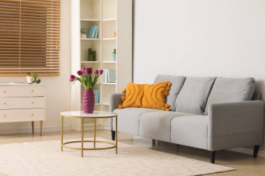 Masanın üzerinde güzel mor laleler olan modern oturma odası ve vazo.