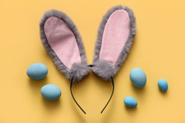 Sarı arka planda Paskalya yumurtası olan tavşan kulaklı.