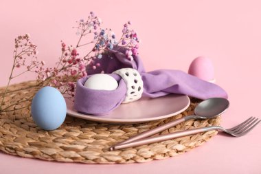 Paskalya için güzel bir masa, pembe arka planda yumurtalar ve çiçekler.