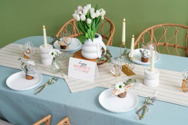 Yeşil duvarın yanındaki Uluslararası Kadınlar Günü kutlamaları için yanan mumlar ve lale çiçekleriyle güzel bir masa.