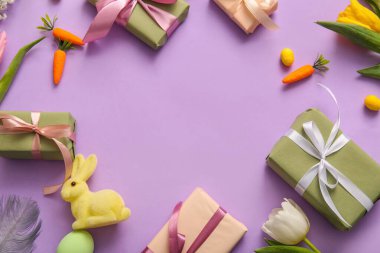 Paskalya tavşanı ve mor arka planda lale çiçekleriyle hediye kutularından yapılmış çerçeve.