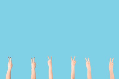 Mavi arka planda barış jestleri gösteren kadın elleri