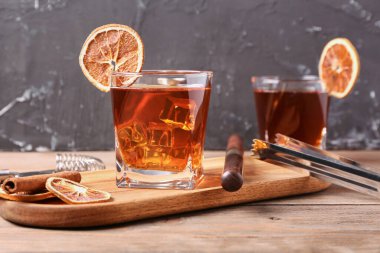 Lezzetli bardaklar, eski moda kokteyller ve ahşap masada portakal dilimleri.