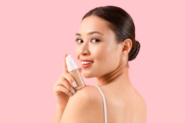 Pembe arka planda makyaj vakfı olan genç Asyalı kadın, yakın plan.