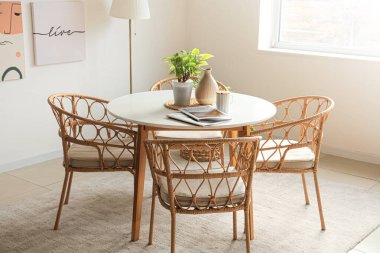 Yemek masasında bitki, vazo, bardak ve dergiler var.