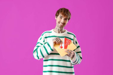 Mor arkaplanda hediye çeki olan dövmeli genç bir adam.